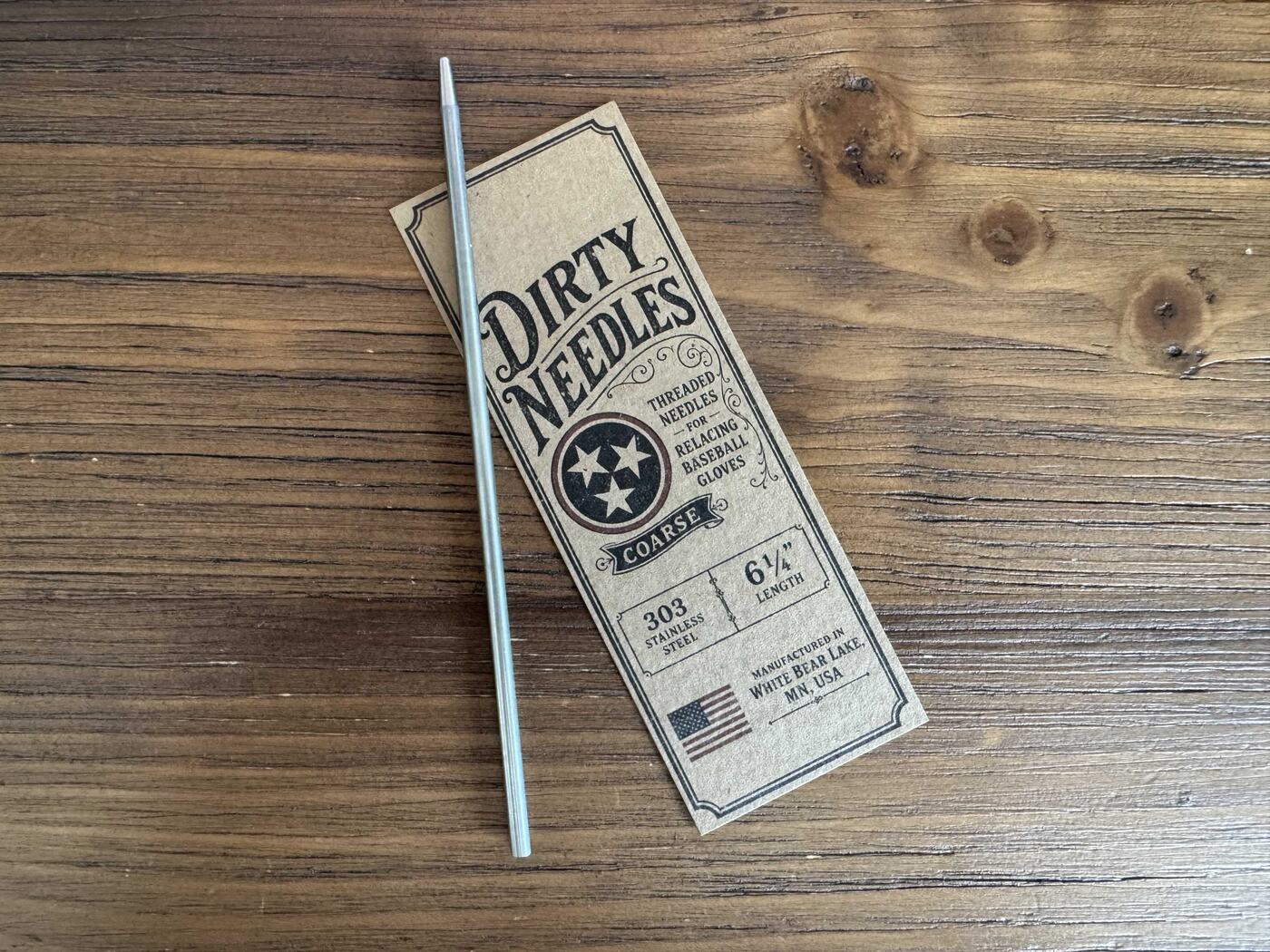 6¼ inch coarse threaded relacing needle beside its kraft Dirty Needles card